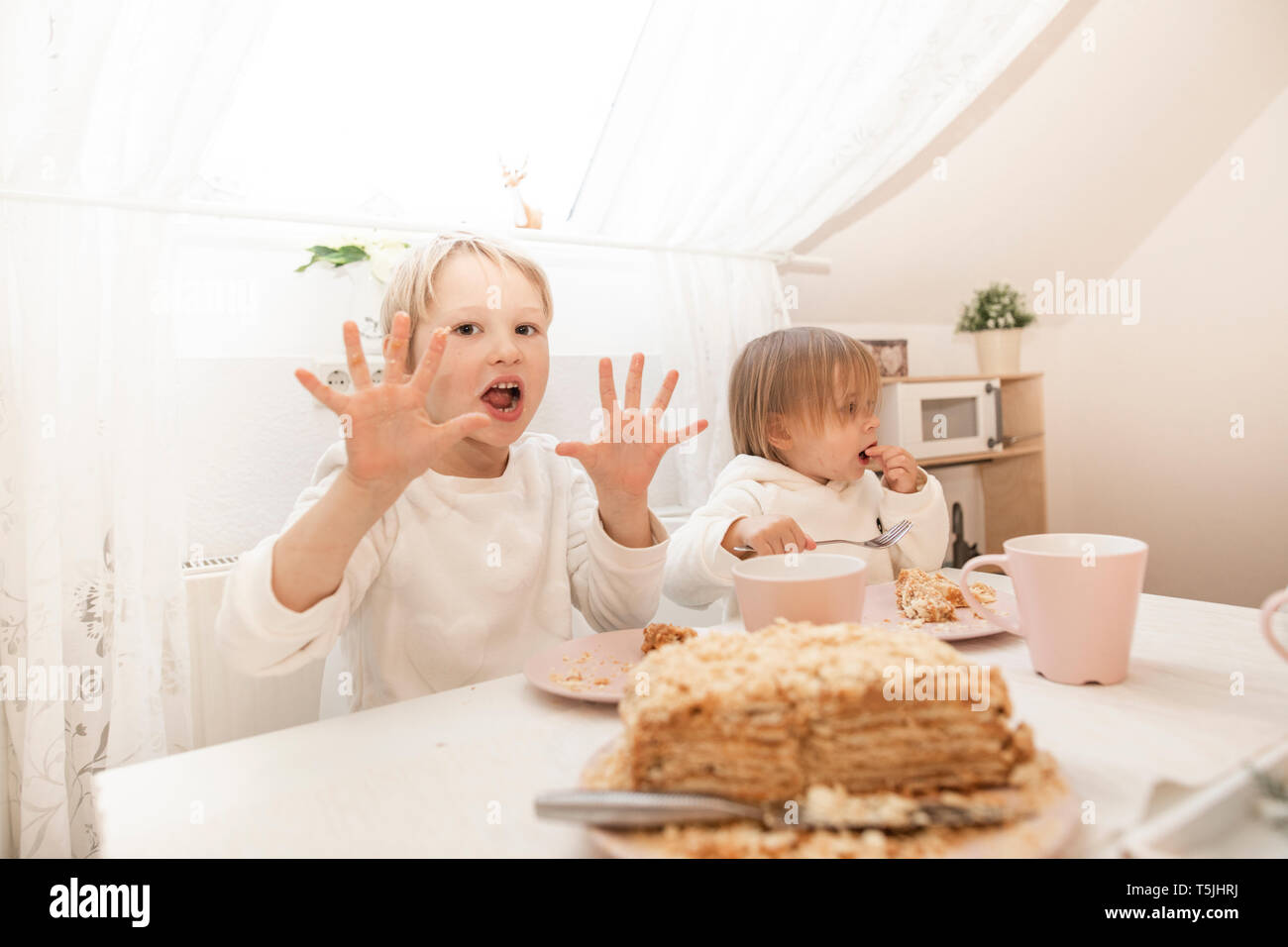 Kinder Kuchen essen in der Küche von ein Apartment im Dachgeschoss Stockfoto