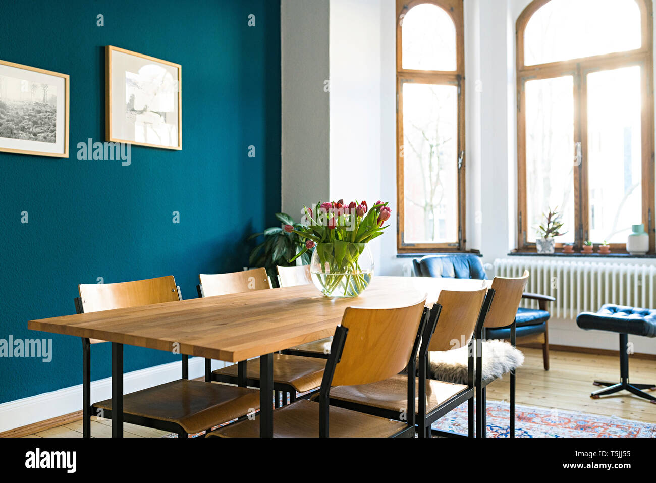 Holztisch und Stühlen mit großer Fensterfront im Wohnzimmer in stilvolles Apartment Stockfoto