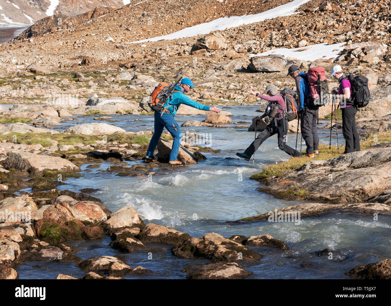 Grönland, Sermersooq, Kulusuk, Schweizerland Alpen, Gruppe von Menschen Bach überqueren Stockfoto