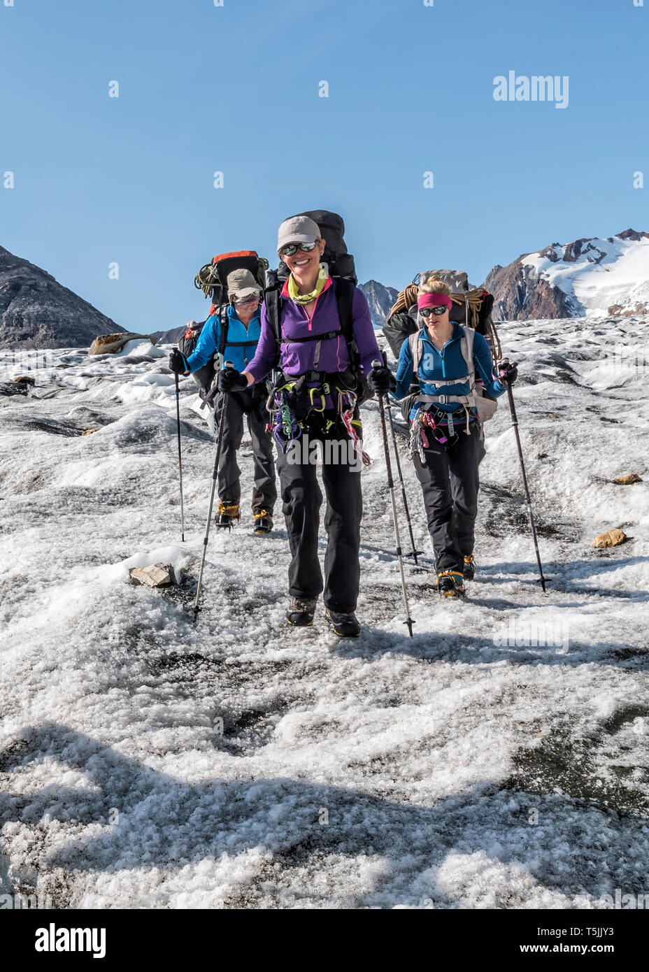 Grönland, Sermersooq, Kulusuk, Schweizerland Alpen, drei lächelnde Menschen wandern in der verschneiten Bergwelt Stockfoto