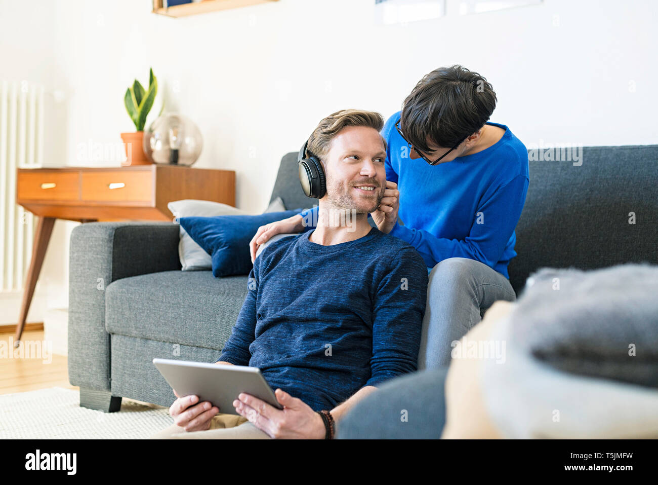 Casual Paar mit Kopfhörern entspannt auf Lounge Couch in ihrer modernen Wohnzimmer Stockfoto