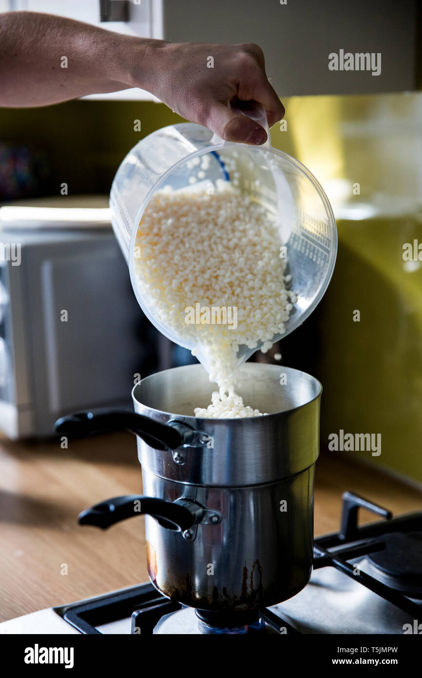 In der Nähe der Person gießen Wachs Granulat für handgemachte Kerzen in Topf zum Schmelzen. Stockfoto