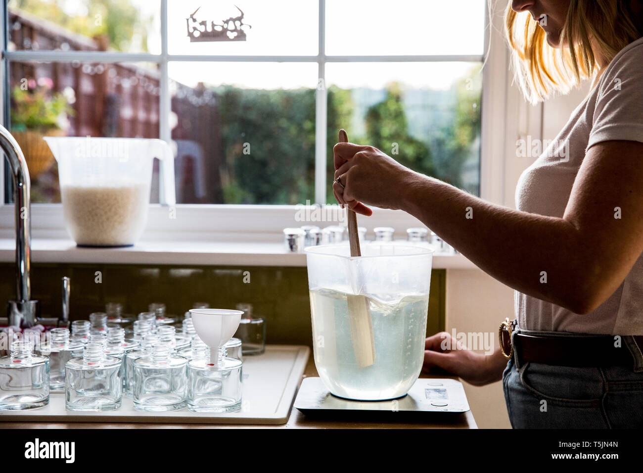 Frau, die in der heimischen Küche, sodass jar Kerzen. Stockfoto