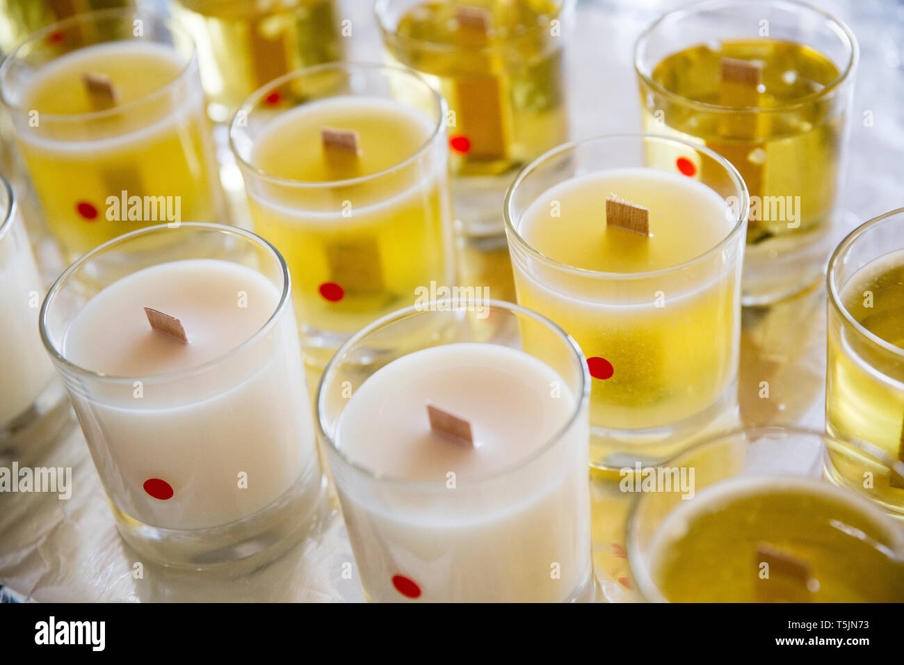 Hohen winkel Nahaufnahme von handgemachten Weißen und Gelben jar Kerzen mit hölzernen Docht. Stockfoto