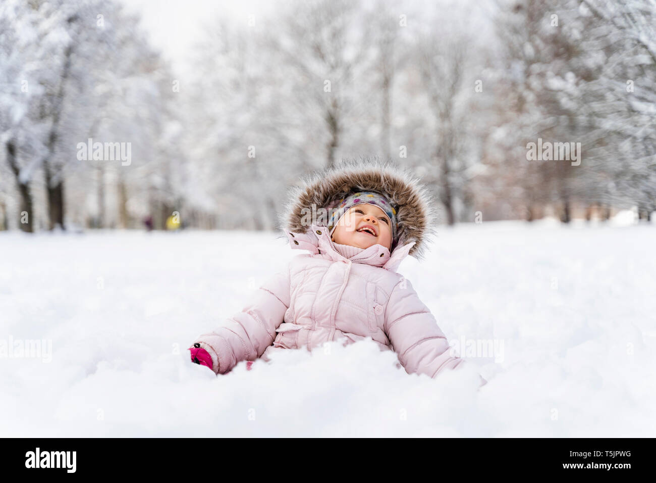 Süße kleine Mädchen sitzen im Schnee im Winter Stockfoto