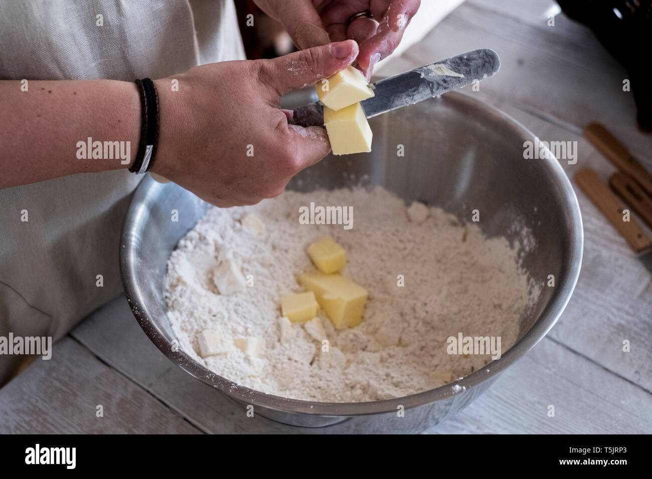 Hohen Winkel in der Nähe der Person mischen Butter und Mehl für die in Metall Schüssel zerbröseln. Stockfoto