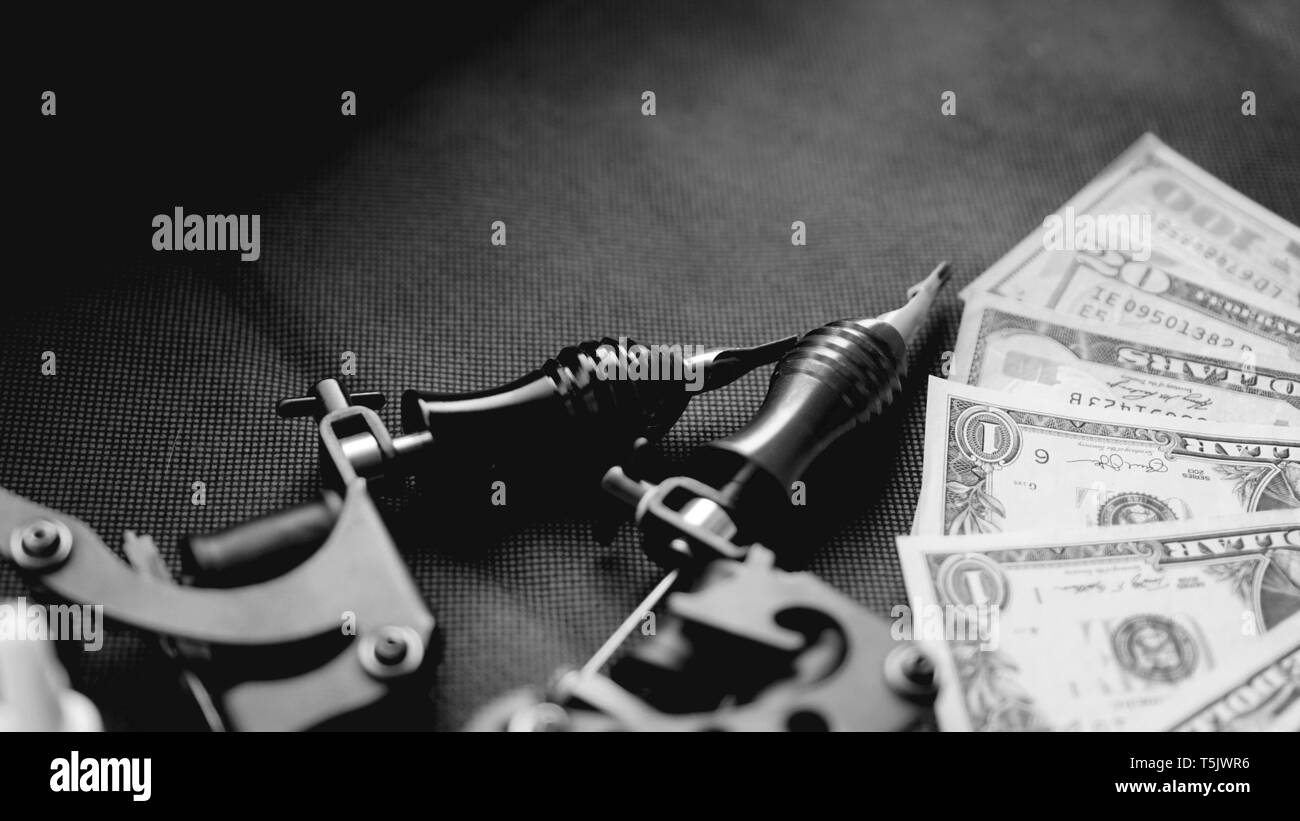Tattoo Maschinen auf einem schwarzen Hintergrund und Dollar. Tattoo Kunst Konzept. Geld für tattoo Stockfoto