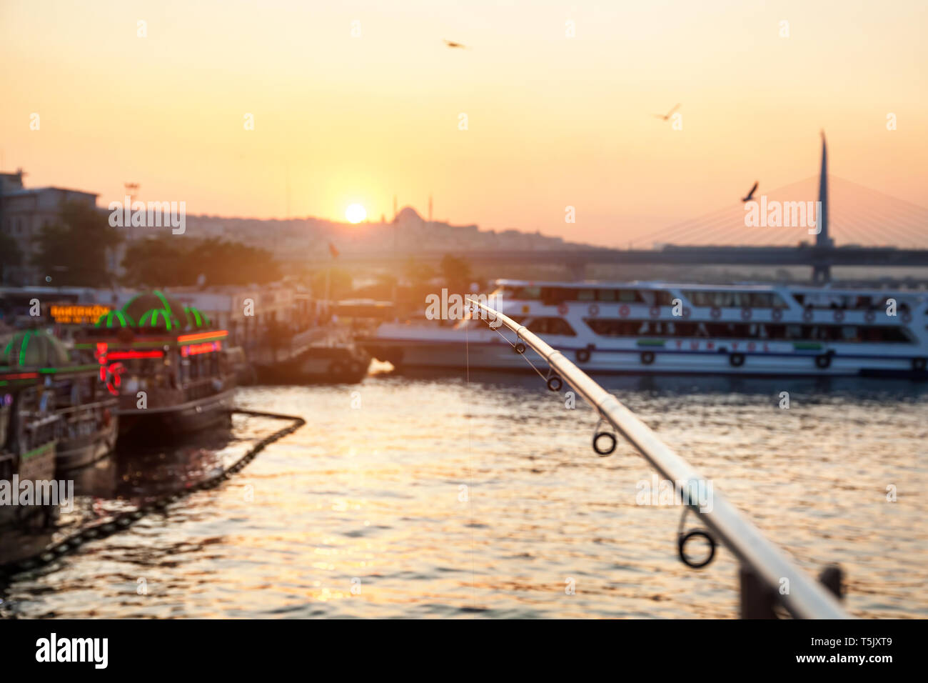 Angelrute im Galata Brücke mit Blick auf die Schiffe bei Sonnenuntergang in Istanbul, Türkei Stockfoto