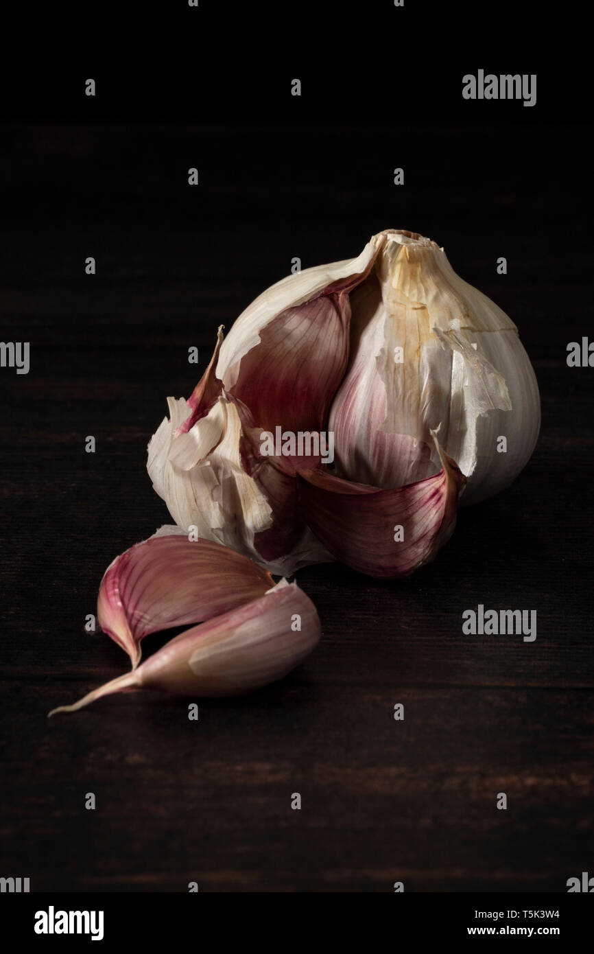 Knoblauch Zwiebel und Knoblauchzehen auf dunklen Kammer Stockfoto