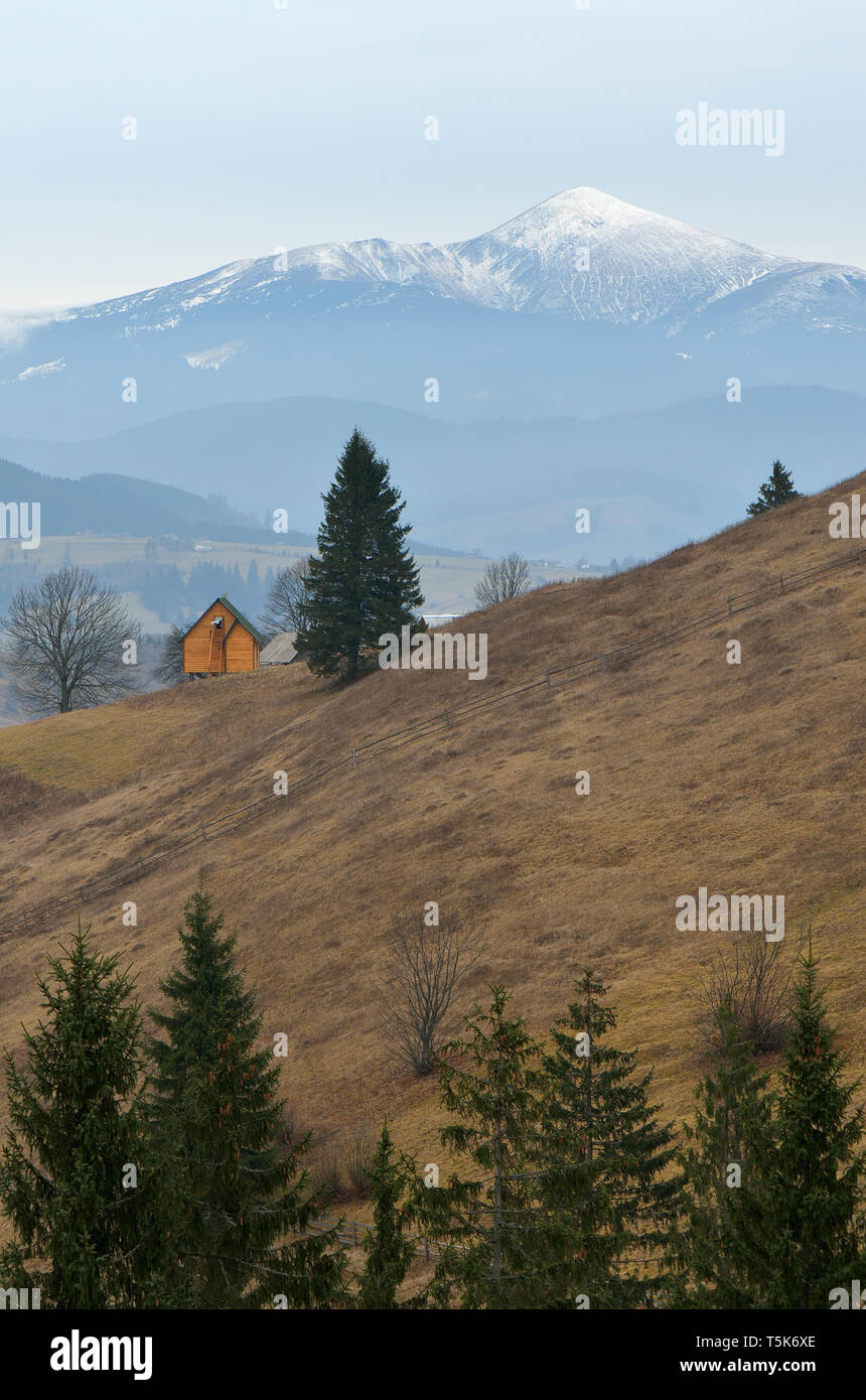 Lonely Holz- Haus in den Bergen. Frühling Landschaft mit schneebedeckten Gipfeln Stockfoto