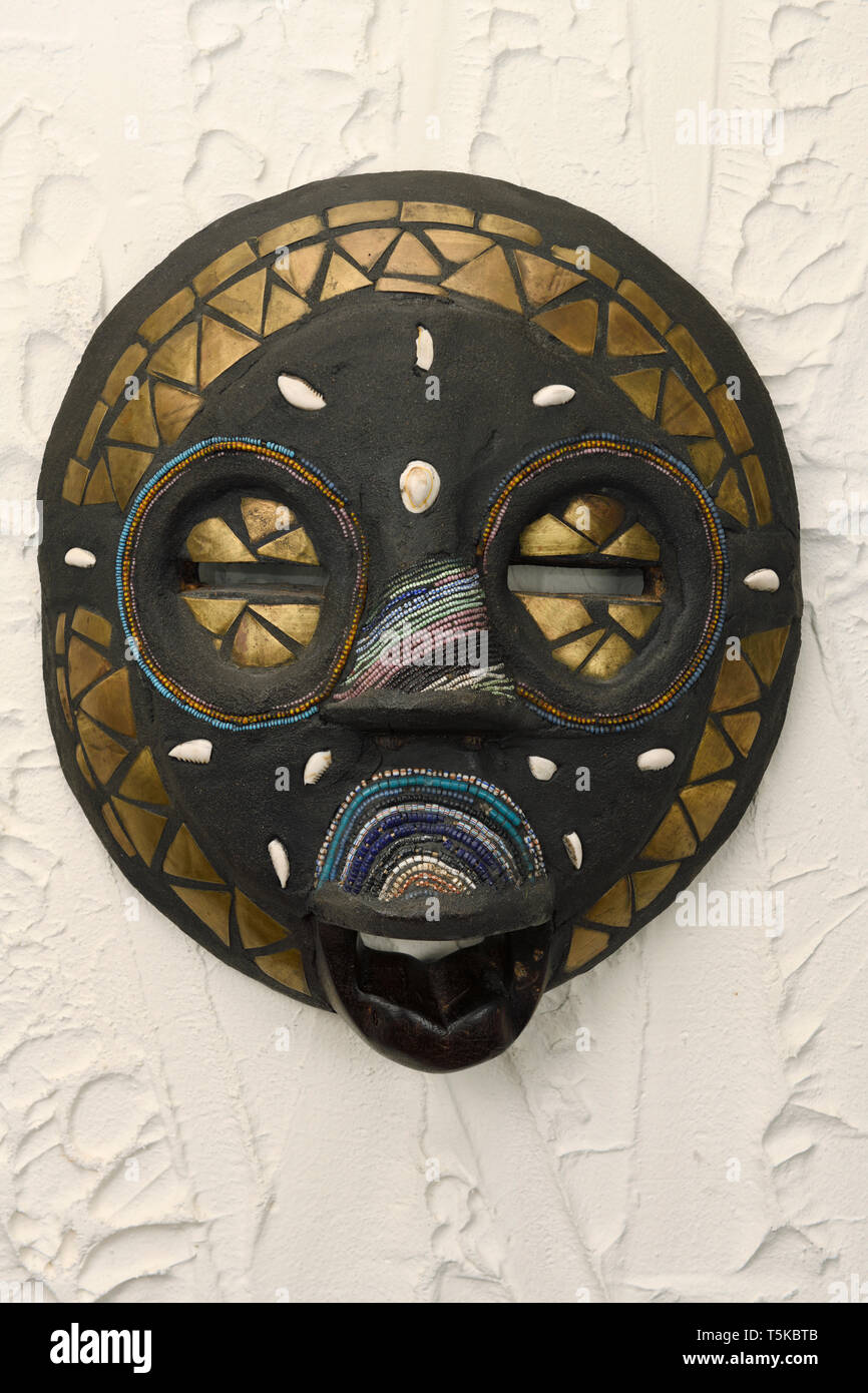 Hand Made African tribal Okyeame Baluba Maske mit Perlen Schalen aus Holz und Messing auf einer verputzten Wand Stockfoto
