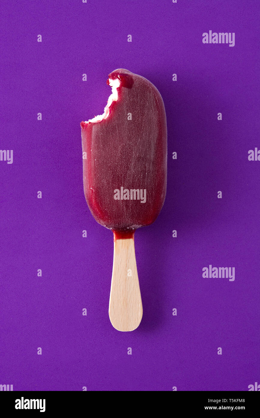 Gebissen Erdbeere popsicle auf Violett Hintergrund. Ansicht von oben Stockfoto