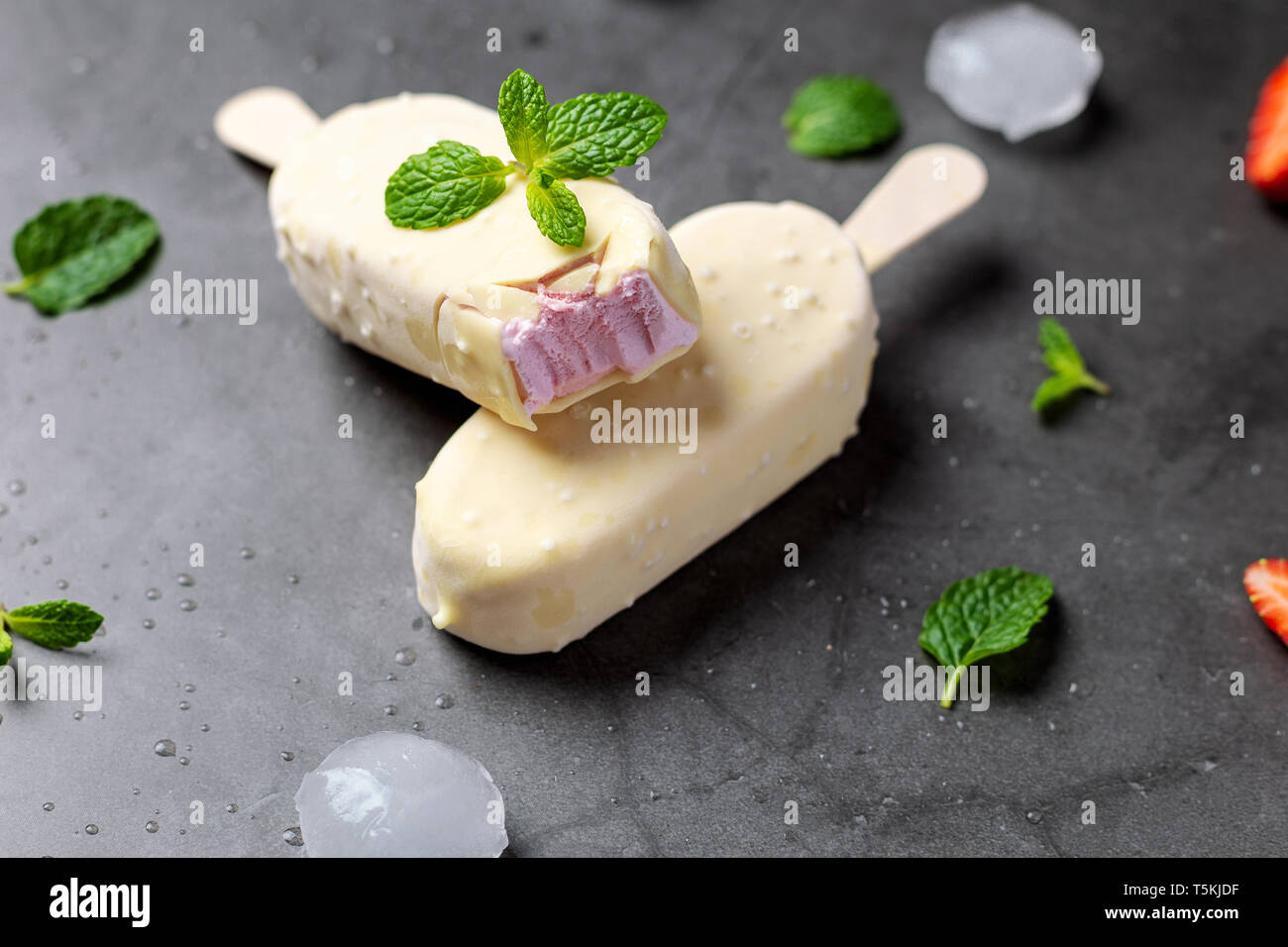 Erdbeereis Stick mit weißer Schokolade auf schwarzem Marmor tisch Stockfoto
