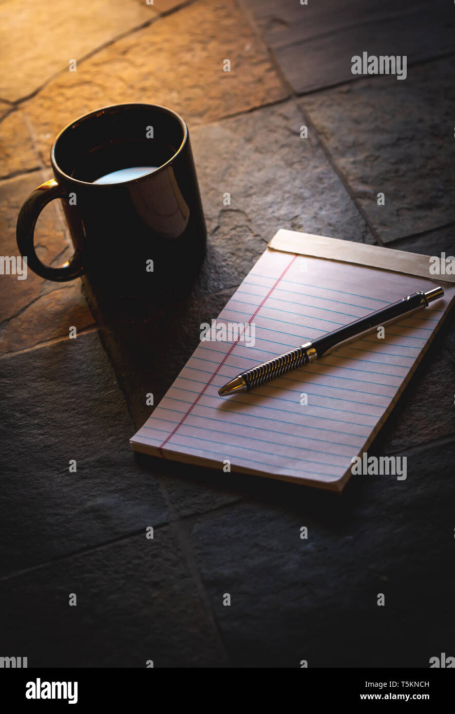 Schwarze Becher Kaffee auf einem steinernen Tisch neben einem Notebook am frühen Morgen Licht des Frühlings. Die sich früh auf die Organisation und produktiv zu arbeiten. Stockfoto