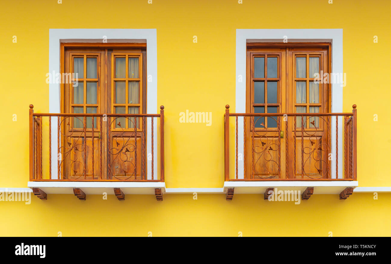 Zwei Kolonialstil zitronengelb Balkone mit hölzernen Rahmen und Dekorationen in der historischen Altstadt von Cuenca, Ecuador. Stockfoto
