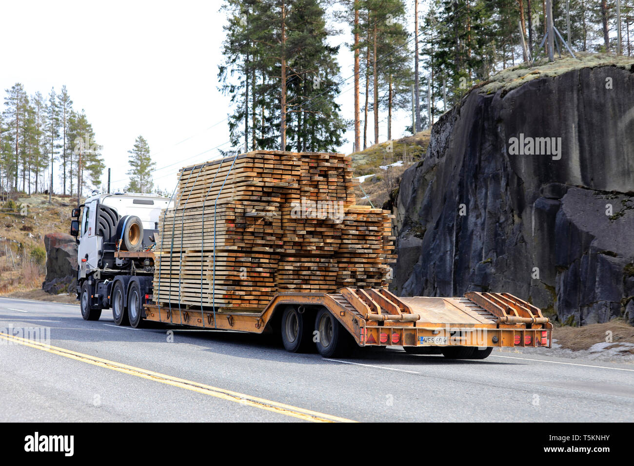 Salo, Finnland - 19 April, 2019: Fahrzeug zieht eine schwere Last von Schnittholz auf Schwanenhals Anhänger auf der Autobahn an einem Tag im Frühling, Ansicht von hinten. Stockfoto