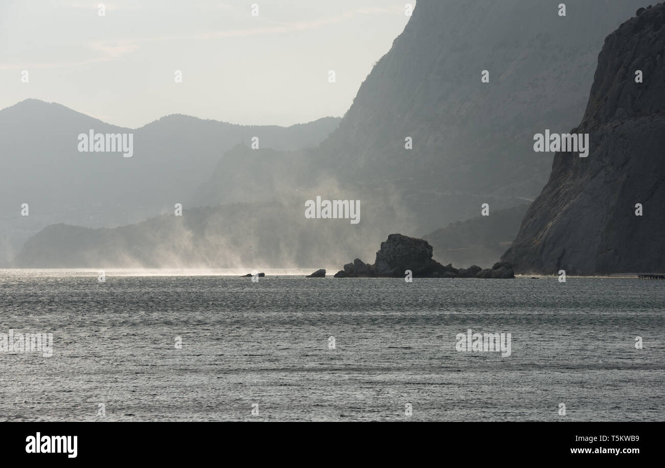 Malerische Ansicht von Sudak zum Root des Sokol (Falcon) Berg mit Feder der Spray durch stürmischen Wind über dem Meer Wasser im Sonnenlicht über Krabbe Insel angehoben Stockfoto
