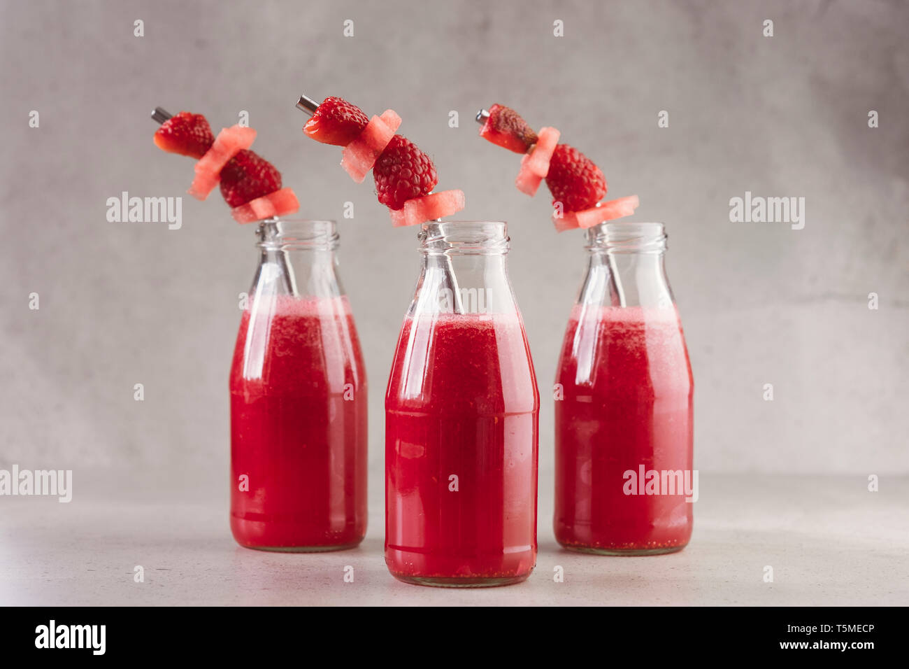 Seitenansicht von Glasflaschen von roten Beeren frischer Saft Stockfoto