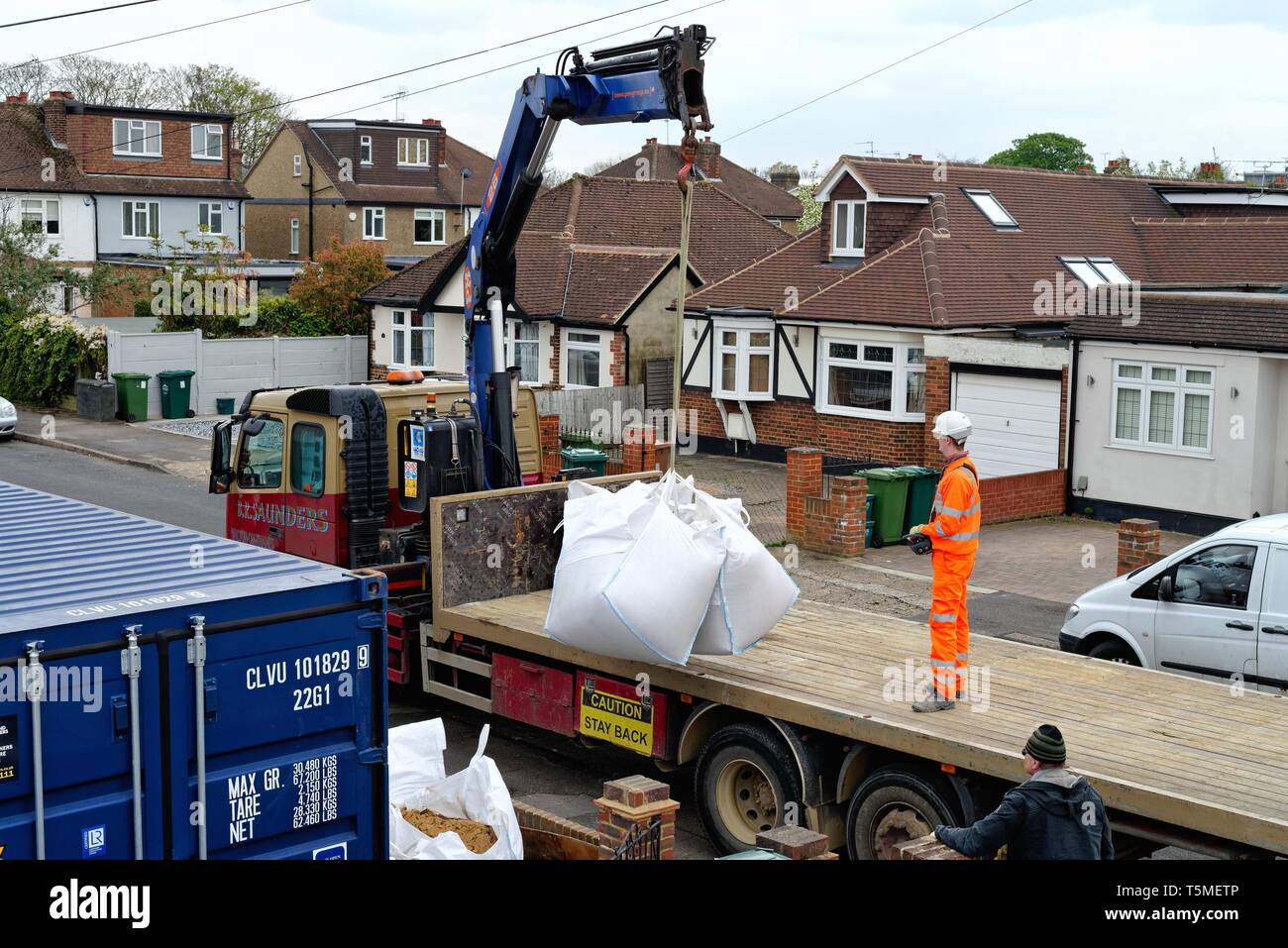 Ein Tieflader Lkw entladen große Säcke mit Sand mit Hilfe einer Hebevorrichtung und Auslieferung an ein privates Haus, für das derzeit Bauarbeiten, Surrey, Großbritannien Stockfoto