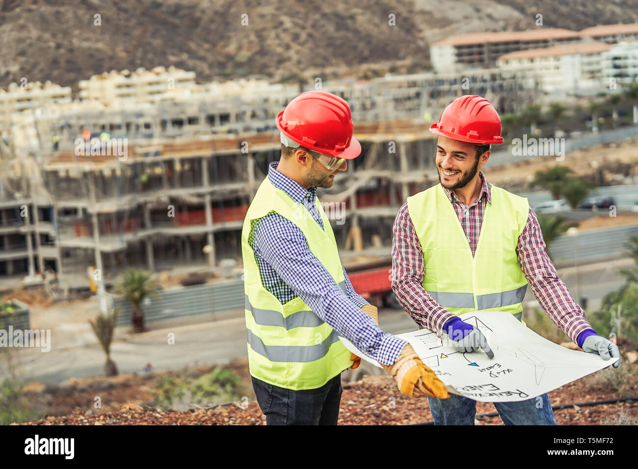 Arbeitnehmer Ingenieure der Diskussion über das neue Gebäude - Junge Baumeister lesen das Projekt in der Baustelle Stockfoto