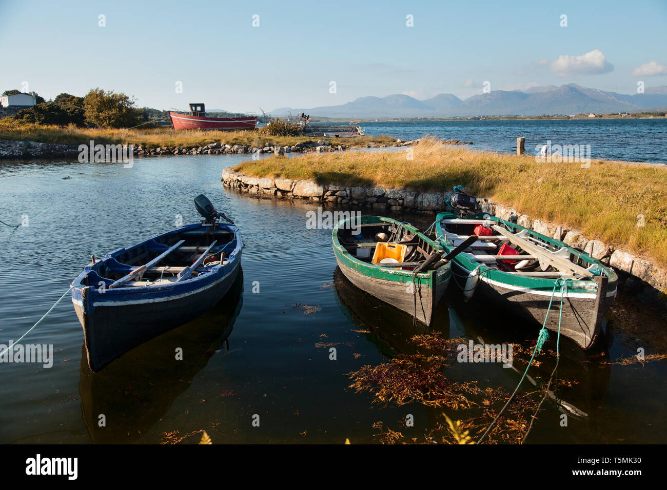 Kleine Fischerboote vertäut an einer kleinen Uferstraße in Connemara, Irland auf den Irischen wilden Atlantik Art und Weise an einem schönen Sommerabend. Stockfoto