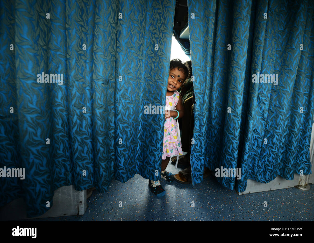 Eine junge tamilische Mädchen spielen Peekaboo im Zug in Tamil Nadu, Indien. Stockfoto