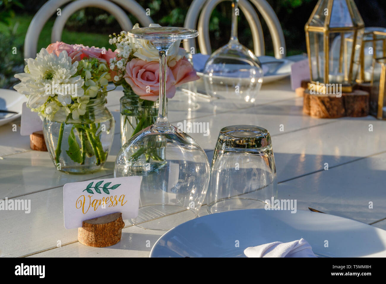 Set Table für eine Hochzeit Abendessen mit Rose Blumensträuße und Glas Lampen eingerichtet. Kalligraphie tag Vanessa. Stockfoto