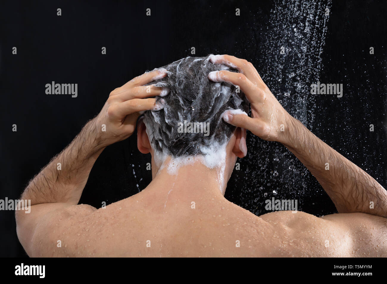 Rückansicht des Menschen Waschen mit Shampoo in der Dusche Stockfoto
