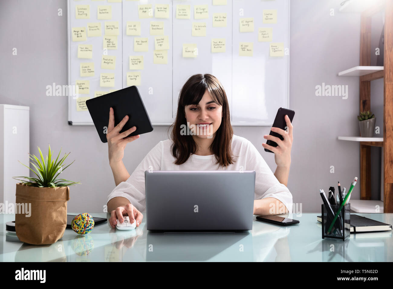 Lächelnden jungen Geschäftsfrau zu tun Multitasking am Arbeitsplatz Stockfoto