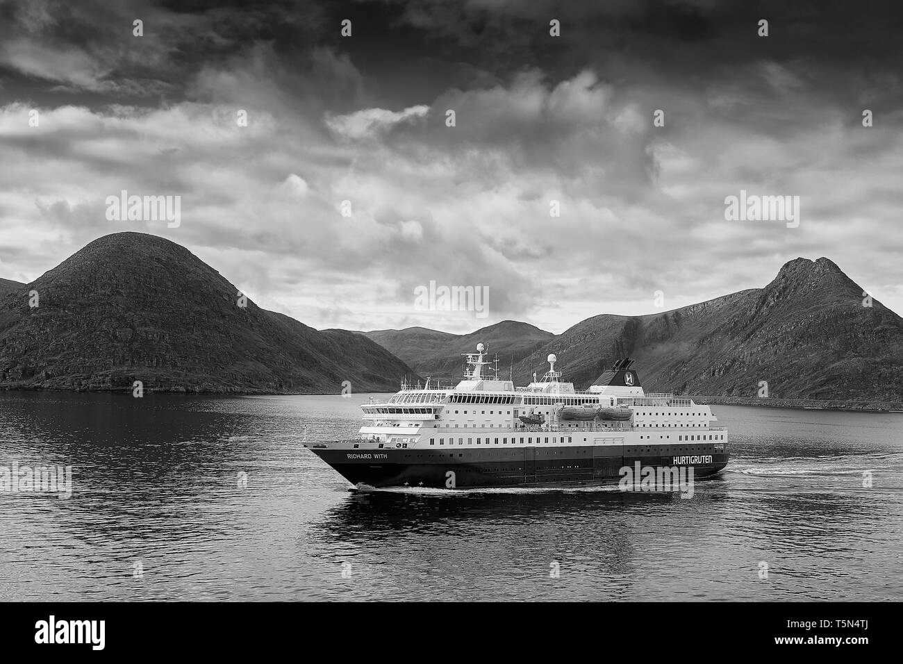 Moody Schwarz-weiß-Foto der norwegischen Hurtigruten-Fähre, MS Richard with, Abfahrt Havøysund, Dampfen in südlicher Richtung. Norwegen. Stockfoto