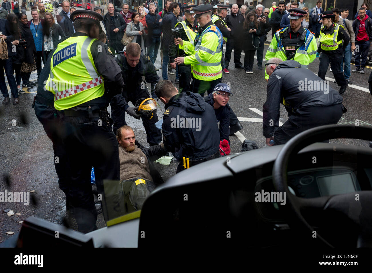 Durch eine stationäre Bus-Fenster sehen, Environmental protesters Kette selbst zusammen und Leim Körperteile auf der Straße in der Fleet Street auf der 11. und letzten Tag der Proteste, Road-Blockaden und Festnahmen in London durch die Klimawandel Kampagne Aussterben Rebellion, am 25. April 2019 in London, England. Stockfoto
