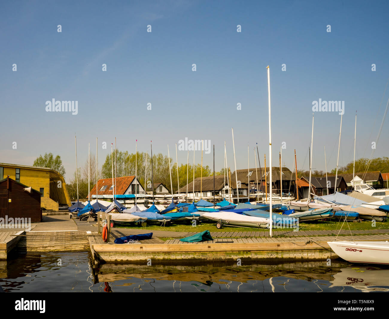 Segelboote auf trockenem Land zwar nicht in Horning Segelclub, Norfolk. In der Ferne sind traditionelle Norfolk Eigenschaften bei Norfolk Reed tha Stockfoto