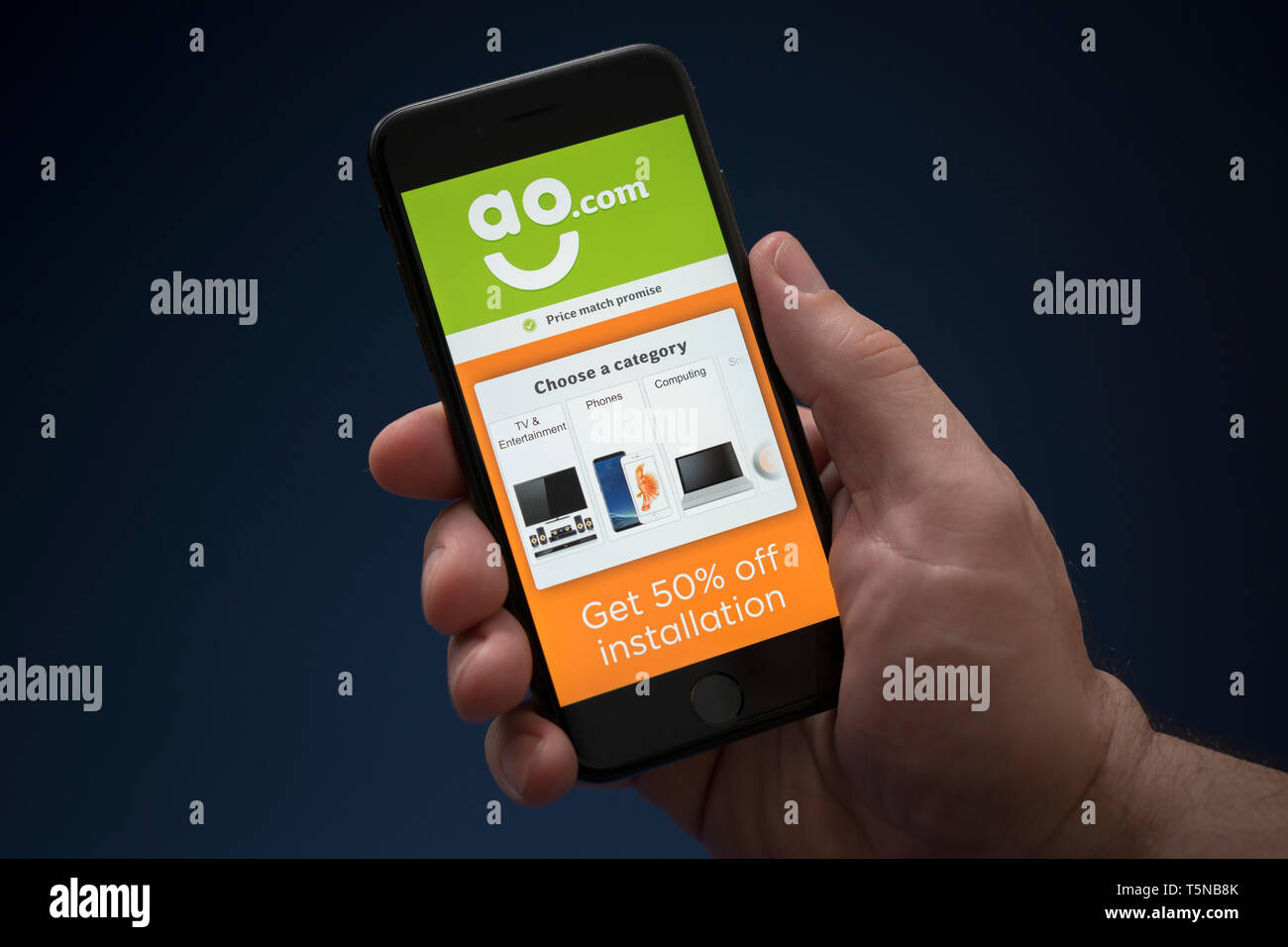 Ein Mann schaut auf seinem iPhone die zeigt die AO.com Logo (nur redaktionelle Nutzung). Stockfoto