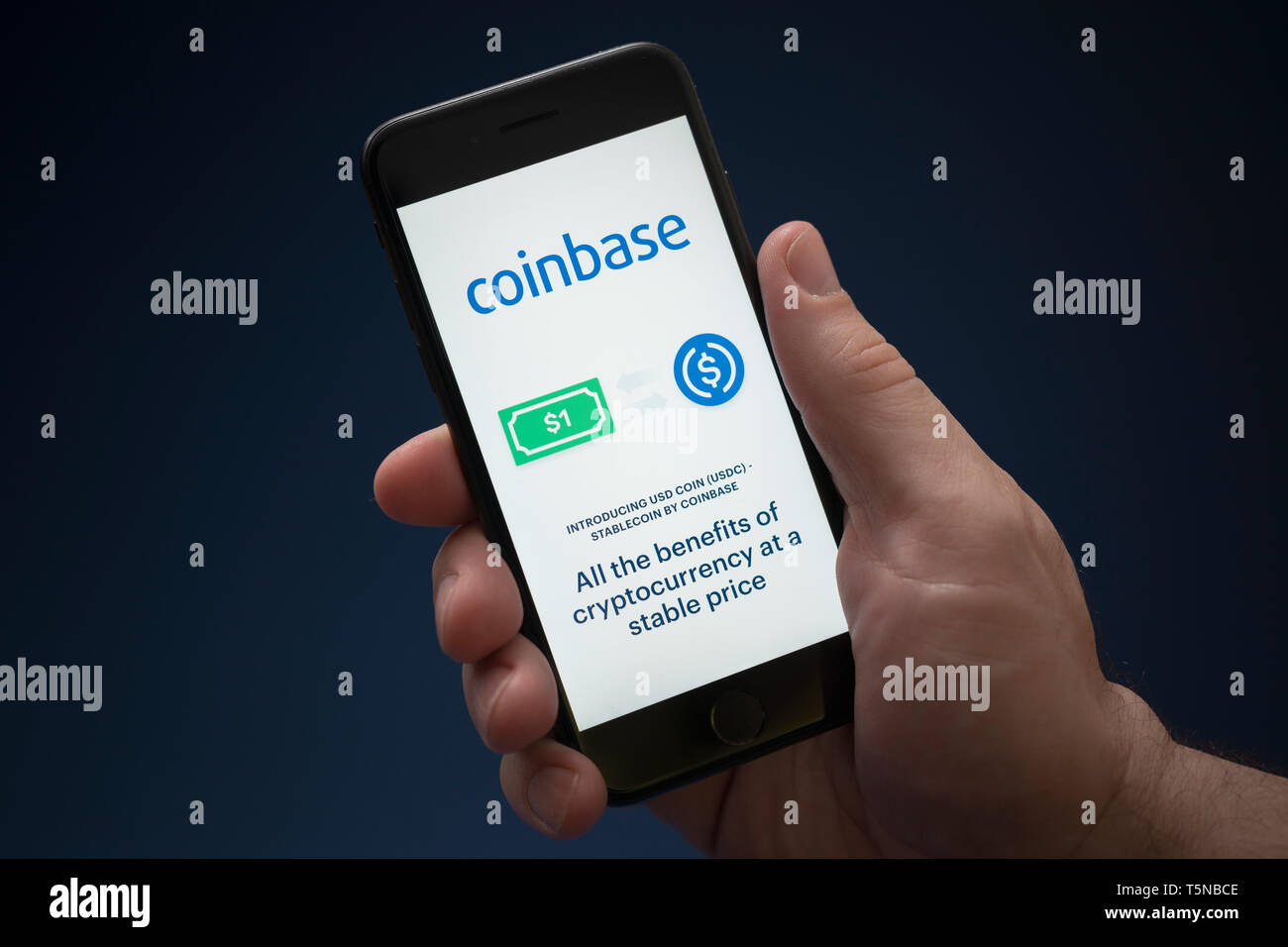 Ein Mann schaut auf seinem iPhone die zeigt die Coinbase Logo (nur redaktionelle Nutzung). Stockfoto