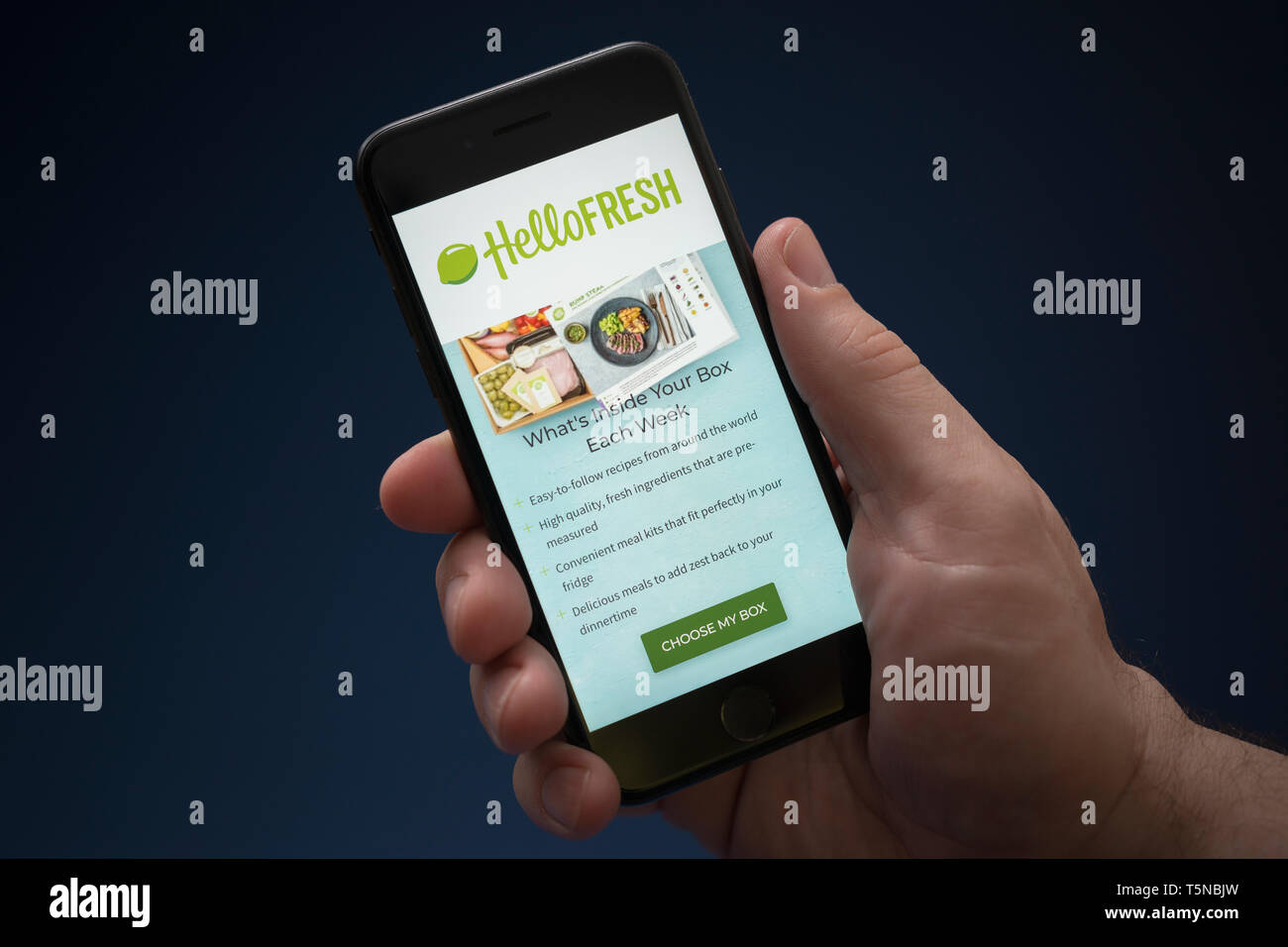 Ein Mann schaut auf seinem iPhone die zeigt die Hallo frisches Logo (nur redaktionelle Nutzung). Stockfoto