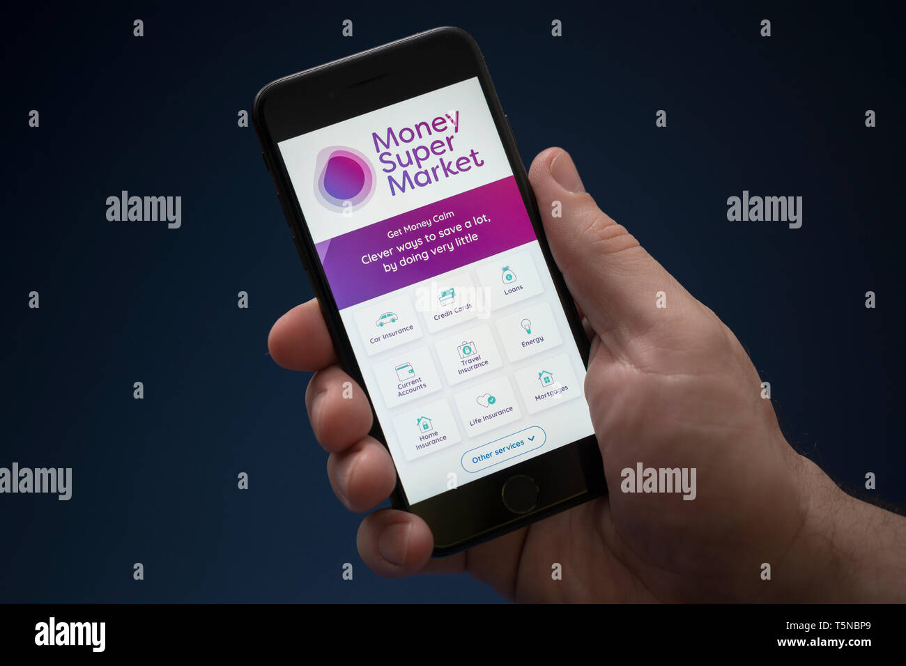 Ein Mann schaut auf seinem iPhone. Das Geld Supermarkt Logo (nur redaktionelle Nutzung). Stockfoto