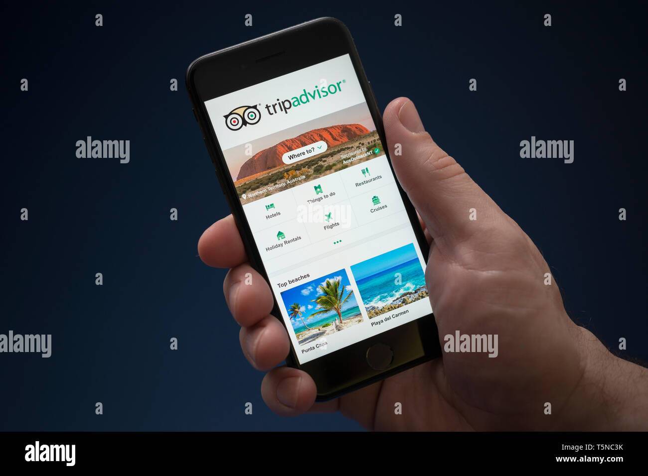 Ein Mann schaut auf seinem iPhone wird der Trip Advisor Logo (nur redaktionelle Nutzung). Stockfoto