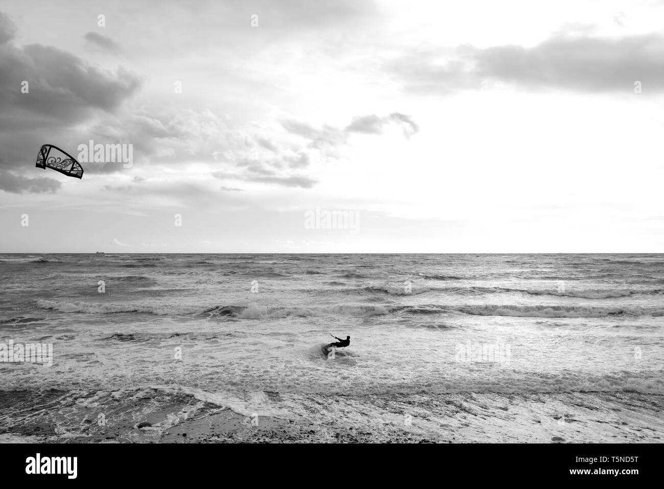 Ein Kitesurfer bei starkem Wind surfen aus der Leistungsschalter durch die Brandung am Bach Strand auf der Insel Wight. Stockfoto