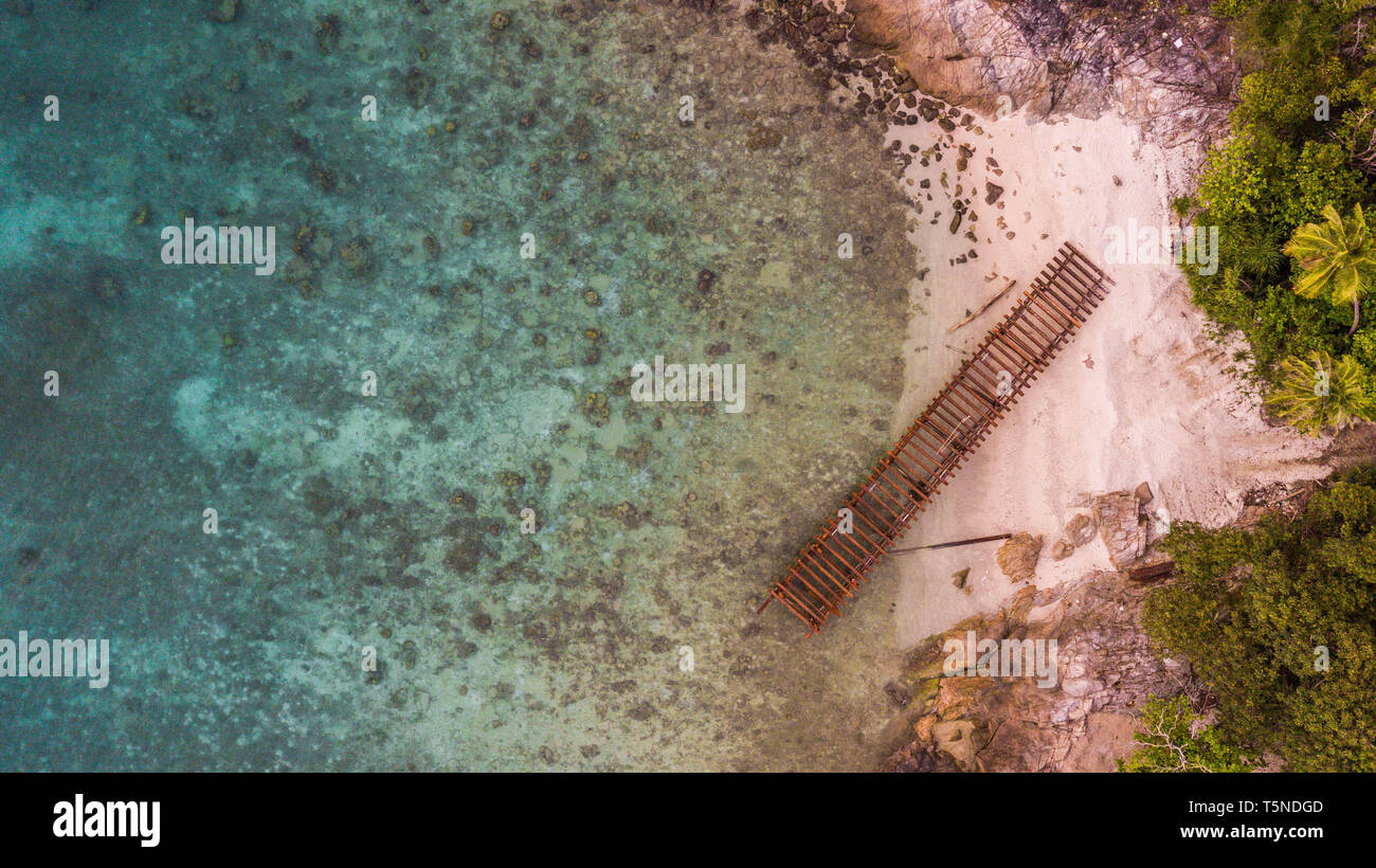 Sommer Strand Hintergrund. Erstaunliche sandige tropischen Strand mit kristallklarem Wasser und alten hölzernen Pier. Antenne Seascape anzeigen. Stockfoto