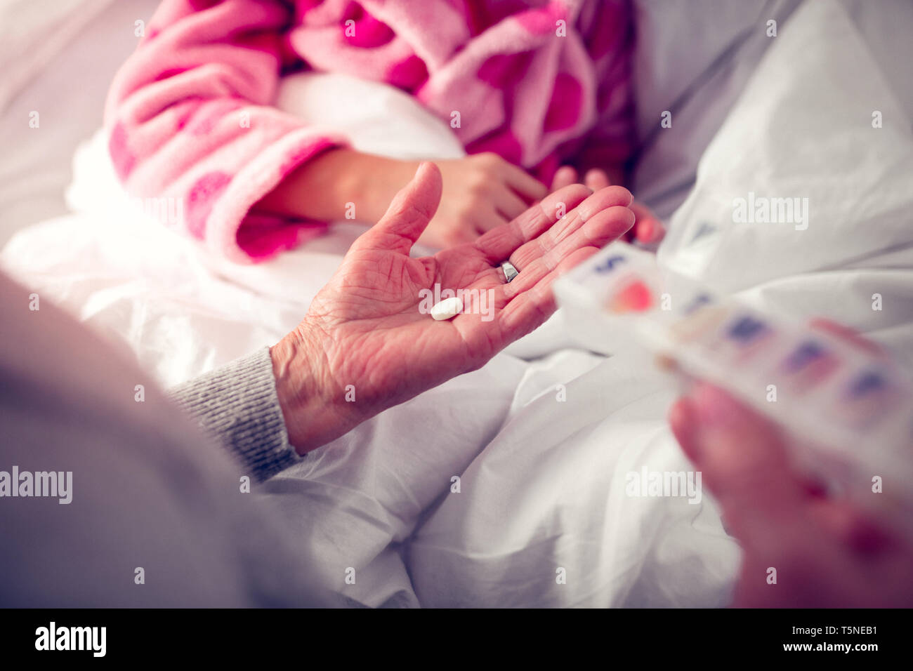 Oma ihre Enkelin in rosa Bademantel geben die Pille Stockfoto