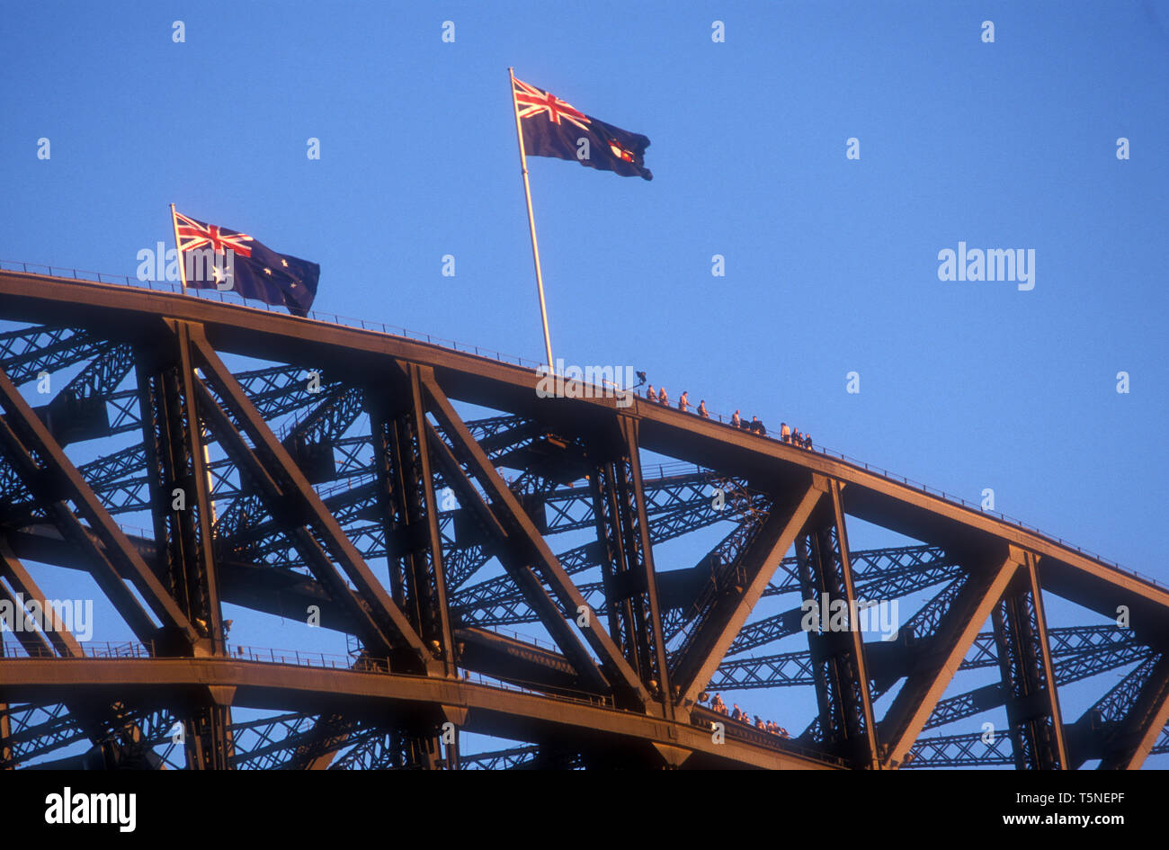 AUSTRALISCHE FLAGGEN FLIEGEN VON DER SPITZE DER SYDNEY HARBOUR BRIDGE GEGEN EINEN BLAUEN HIMMEL, NEW SOUTH WALES, AUSTRALIEN. Stockfoto