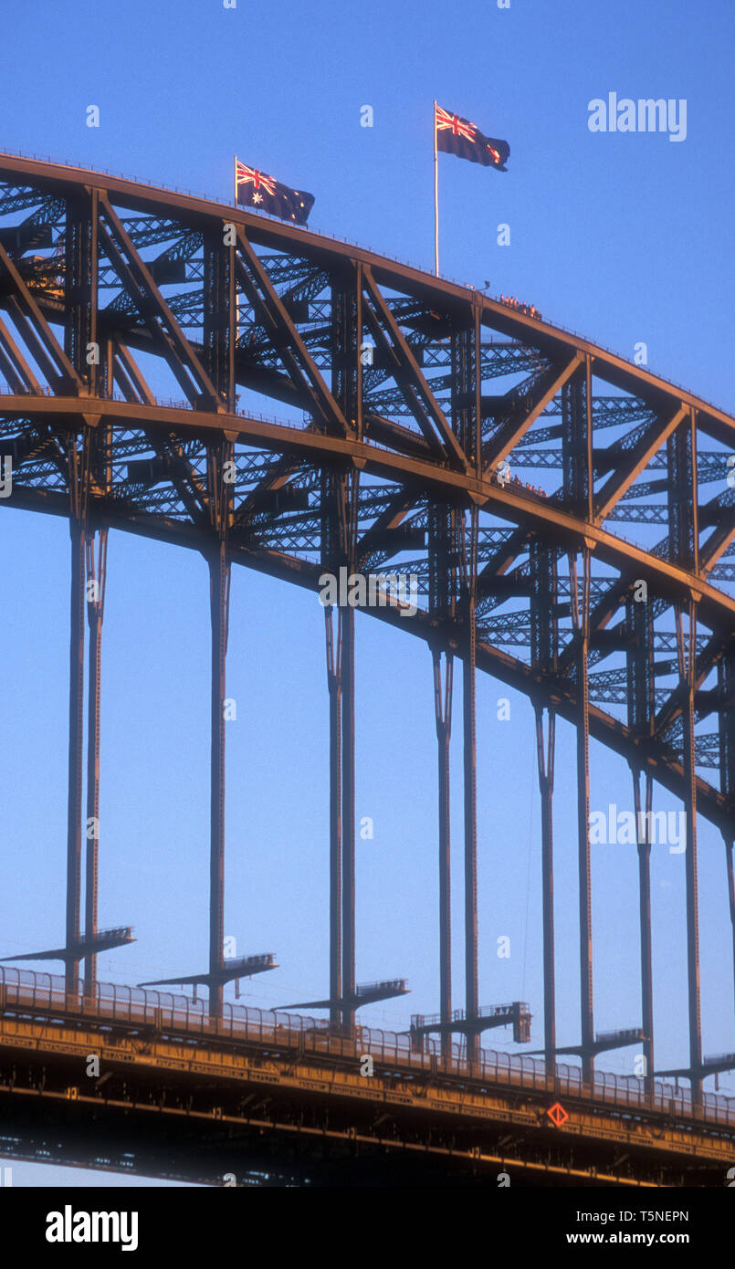 AUSTRALISCHE FLAGGEN FLIEGEN VON DER SPITZE DER SYDNEY HARBOUR BRIDGE GEGEN EINEN BLAUEN HIMMEL, NEW SOUTH WALES, AUSTRALIEN. Stockfoto