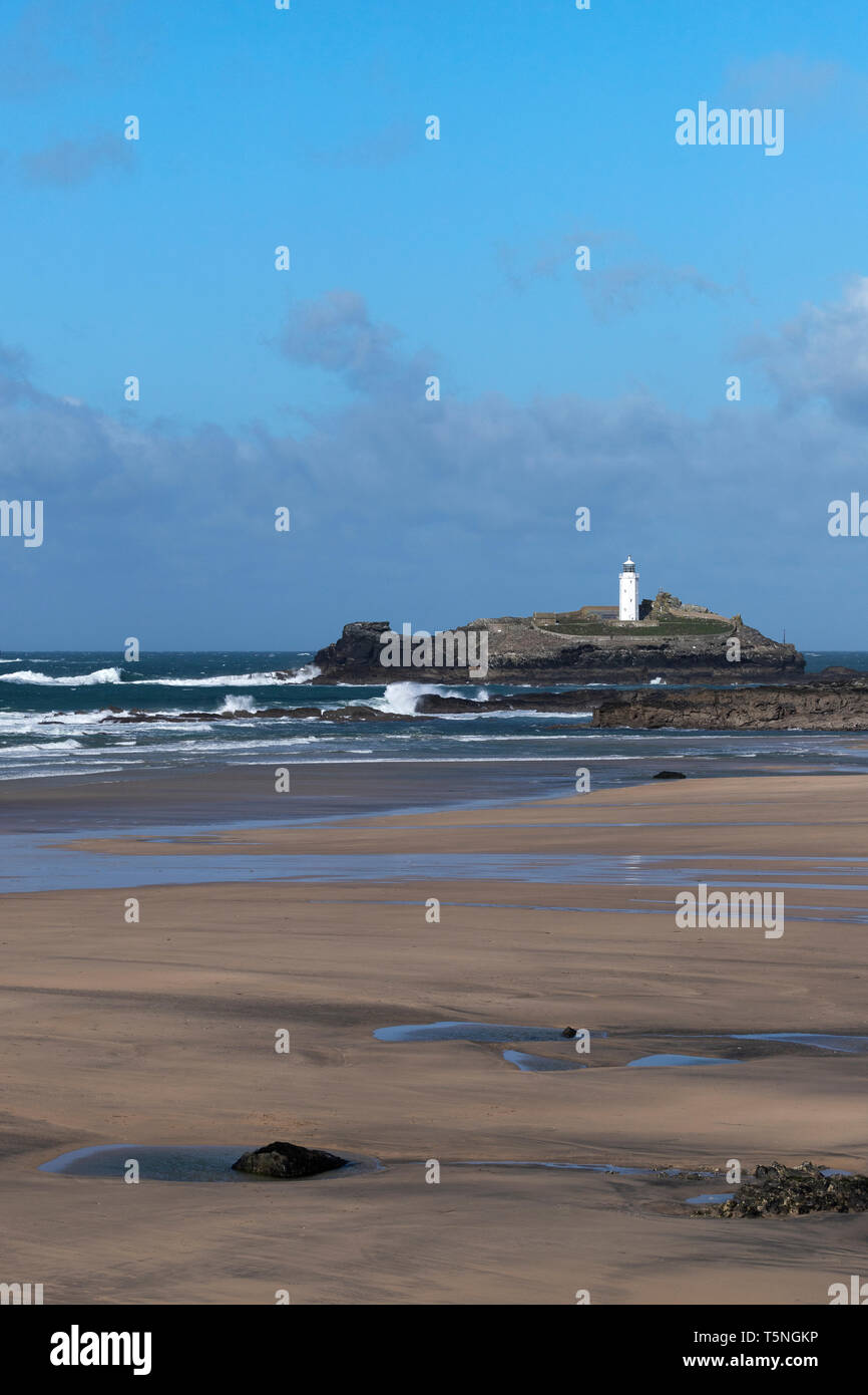 Der Sturm ist vorüber. Eine sonnige Aussicht an einem windigen Tag der Godrevy Leuchtturm über leere Strand. Gwithian, Cornwall. März 2019 Stockfoto