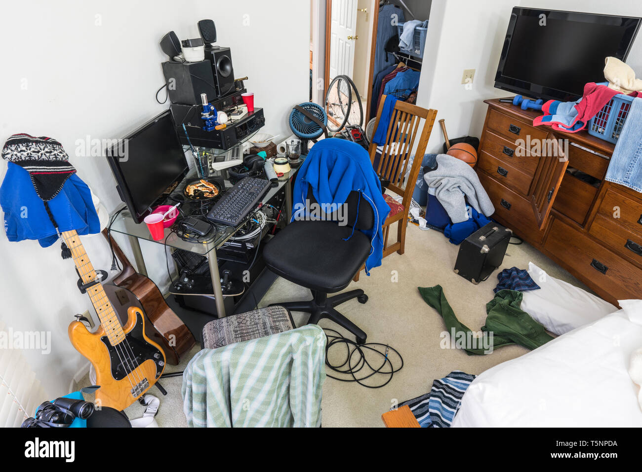 Chaotisch, überladen Jugendjungen Schlafzimmer mit unordentlicher Stapel von Kleidung, Elektronik, Musik und Sport. Stockfoto