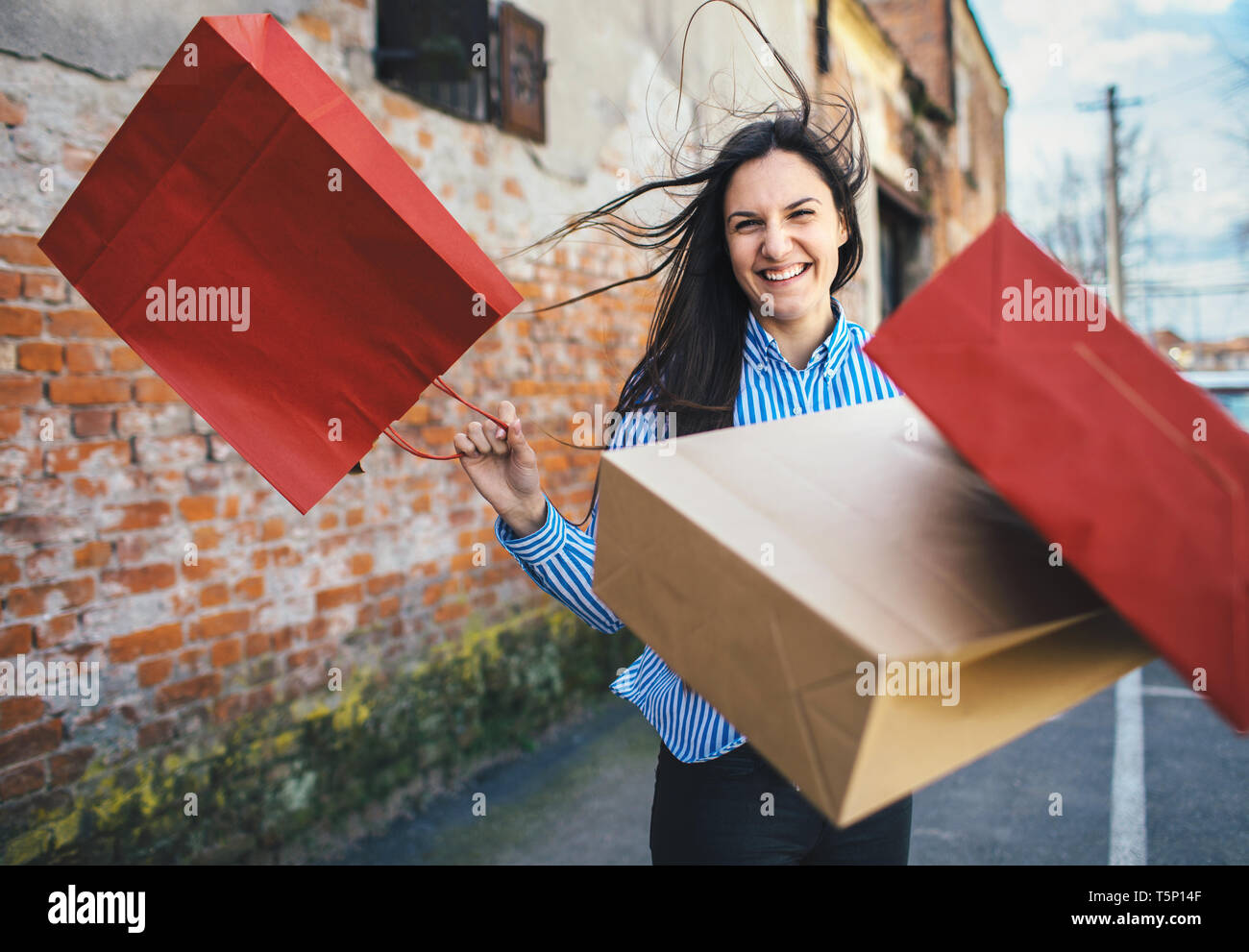 Junge Frau mit Einkaufstüten an der Straße Stockfoto