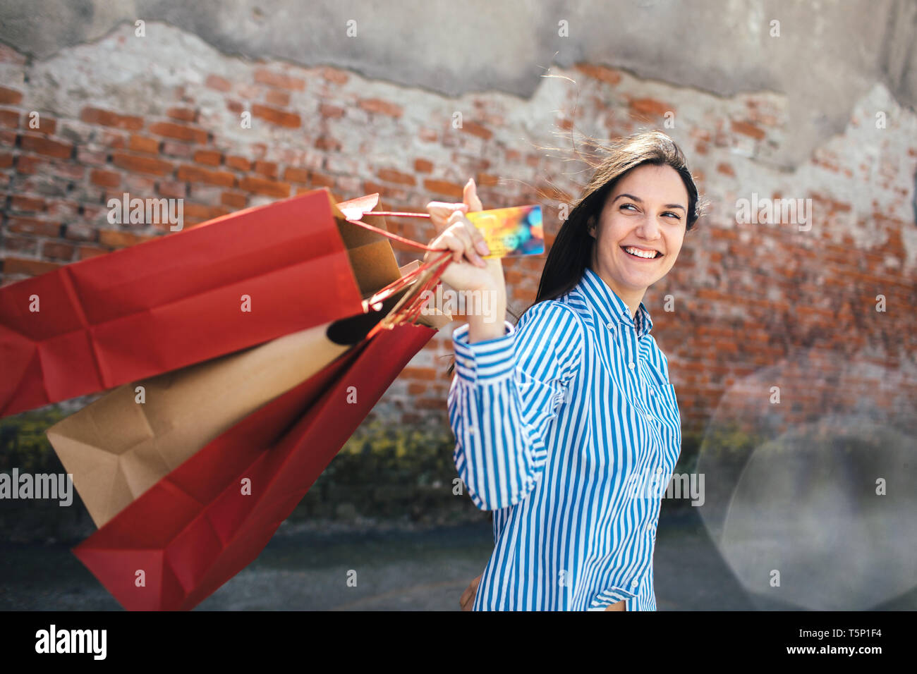 Junge Frau mit Einkaufstüten an der Straße Stockfoto