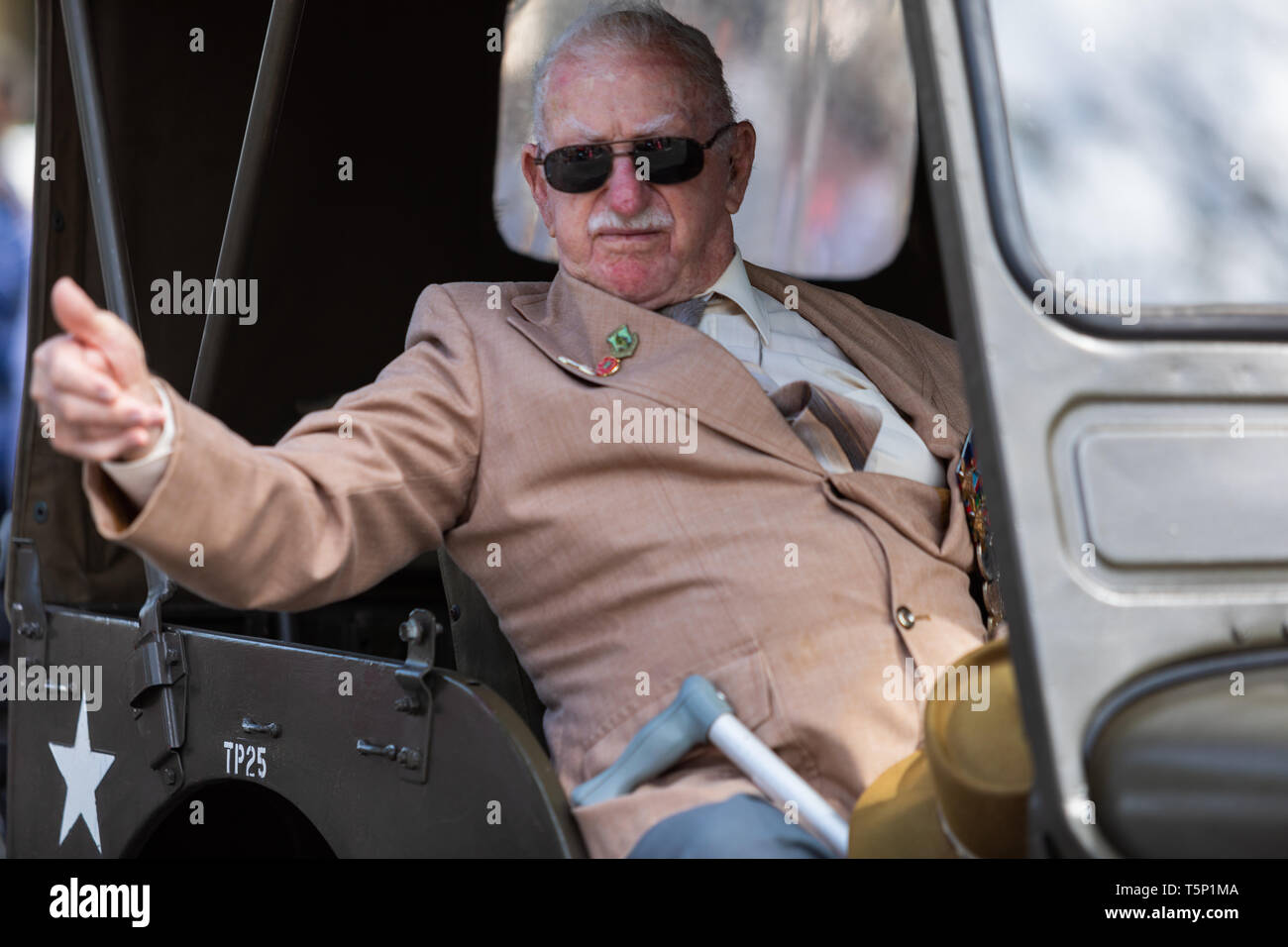 Eine ältere zurück Veteran in seinem Begleitfahrzeug winken und geben Daumen bis zu der Menge jubeln und klatschen für ihn, während der ANZAC Day März Stockfoto