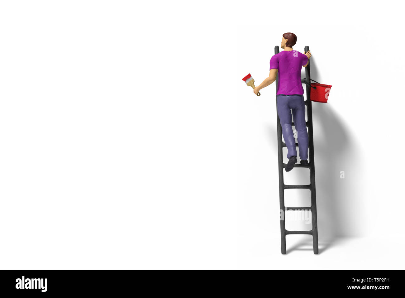 Spielzeug Miniatur Figur Charakter mit Leiter und roter Farbe vor einer Wand Stockfoto