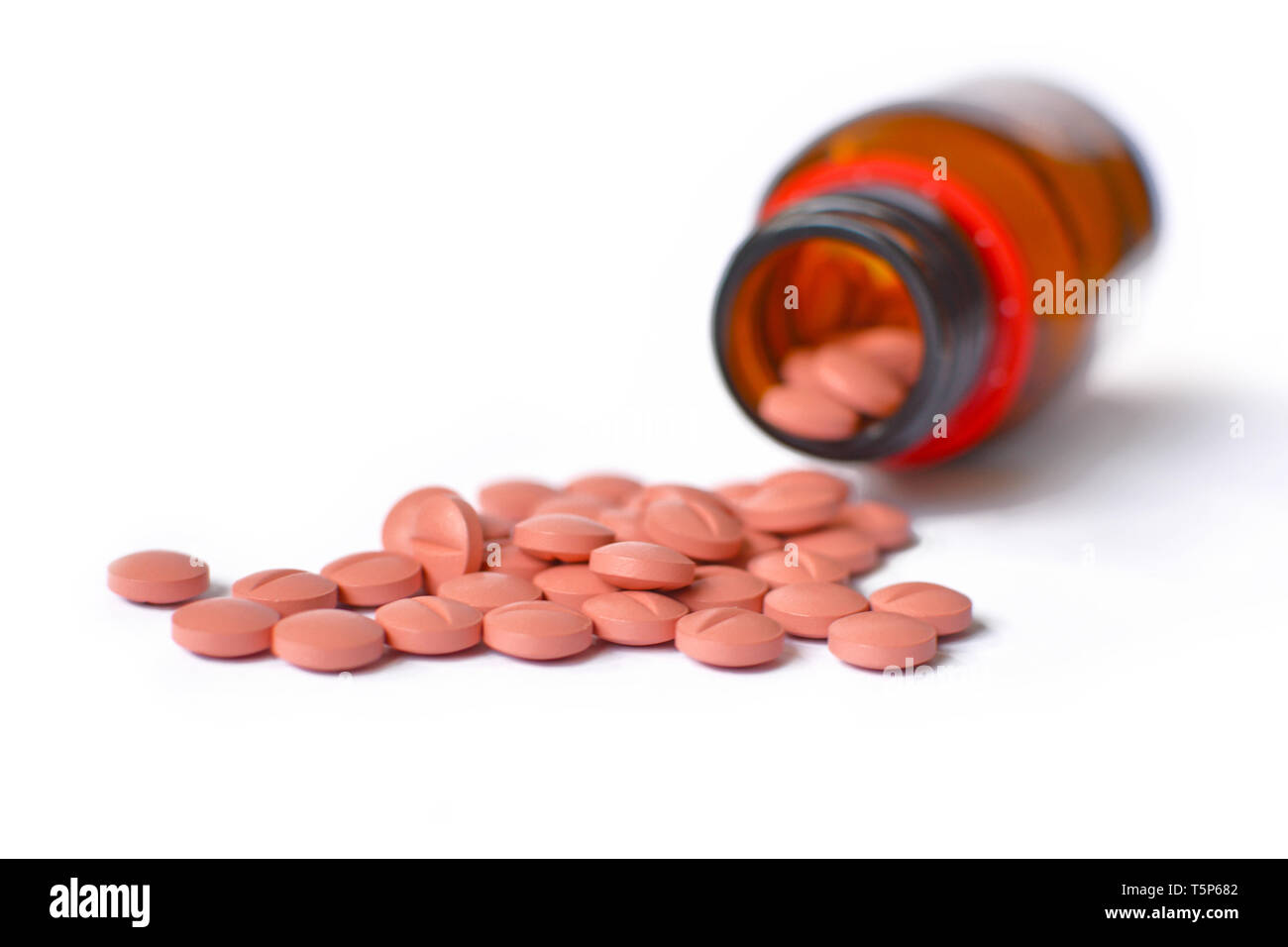 Viele hellrosa medizinische Pillen Verschütten von einer Glasflasche Container auf weißem Hintergrund Stockfoto