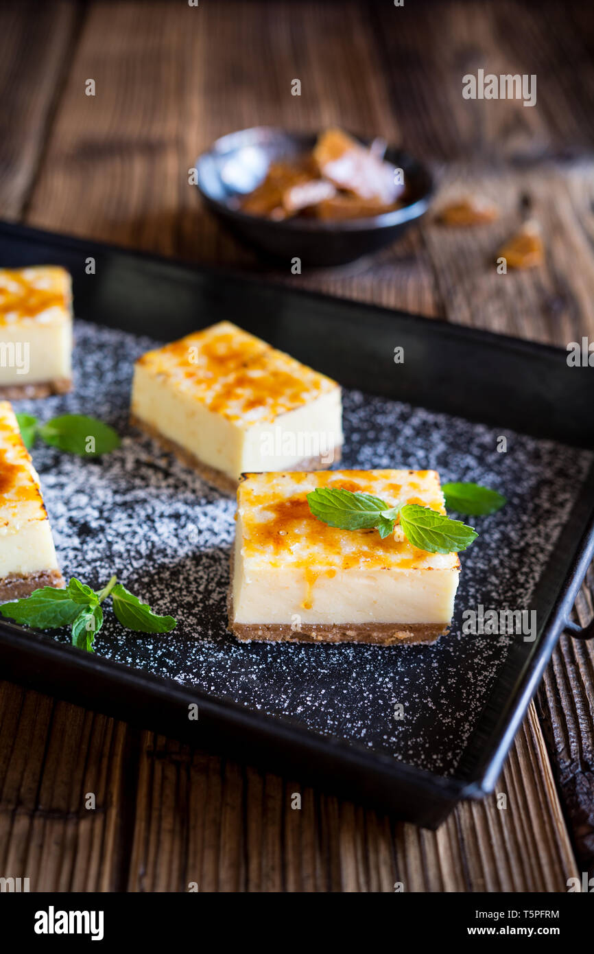 Hausgemachte Crème Brûlée Käsekuchen bars mit Frischkäse, zerkleinert Cookies, gekrönt mit karamellisierten Zucker Stockfoto